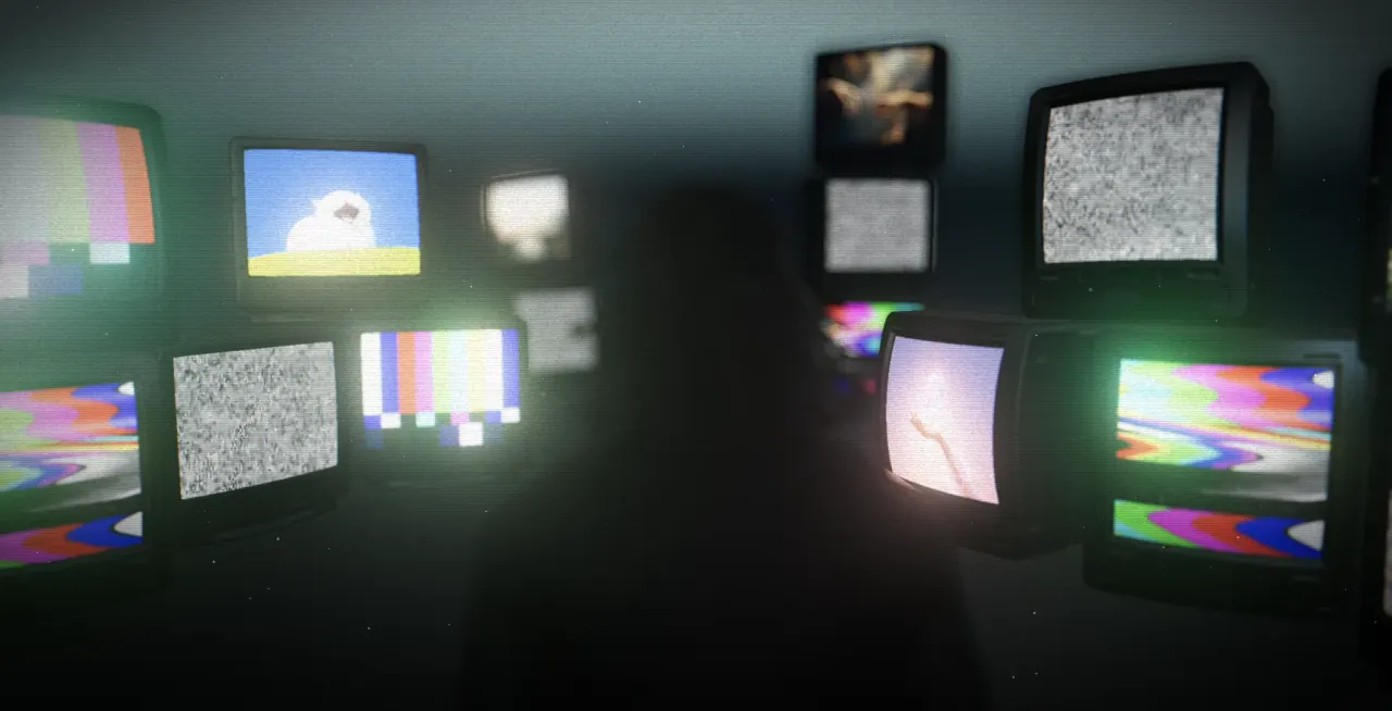A silhouetted filmmaker facing a wall of glowing vintage televisions